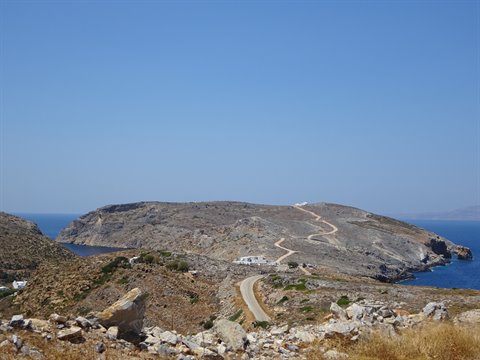 Winding road through dry hills toward blue coves in Sifnos