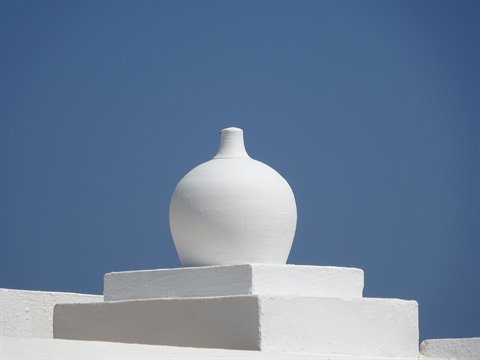 White clay pot on a whitewashed rooftop chimney under blue sky, Sifnos