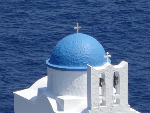 Blue dome and white bell tower of a church above the sea in Sifnos