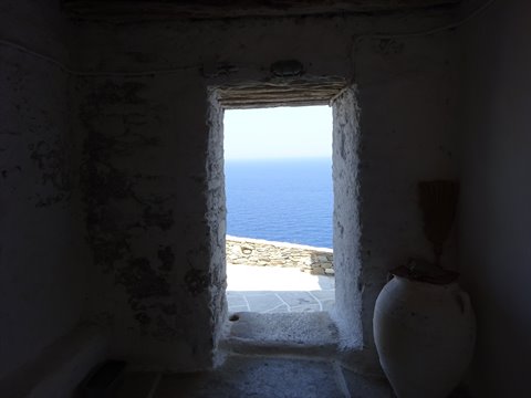 Whitewashed stone doorway with clay jar, Aegean Sea beyond in Sifnos