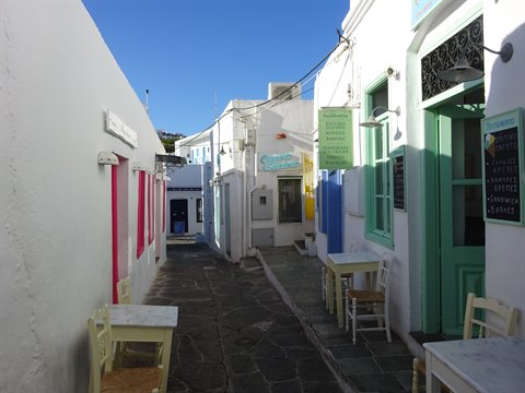 Paved alley in Artemonas, whitewashed houses, green doors and outdoor tables