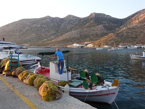 Fisherman on fishing boat with yellow nets at Kamares port, Sifnos