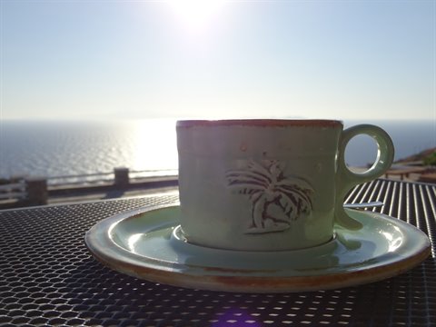 Green ceramic palm cup on a table, Aegean sea shining behind, Sifnos