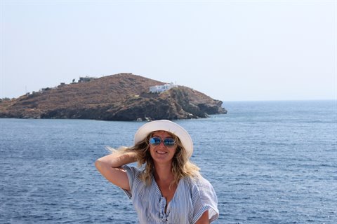 Woman in straw hat in front of the sea and a white Sifnos hill