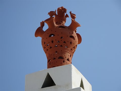 Sifnos terracotta chimney ornament with birds atop whitewashed flue
