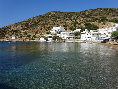 White houses on Faros beach, clear turquoise water and a boat offshore
