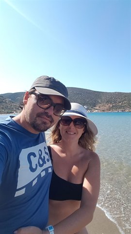 couple taking a selfie on a Sifnos beach, turquoise water and arid hills