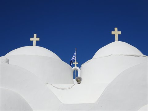 Two white domes with crosses on a Sifnos church, deep blue sky