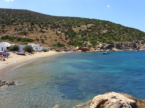 Sandy beach with white houses, blue boat and turquoise sea in Sifnos