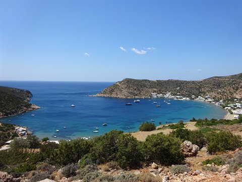 Boats anchored in Vathi's turquoise bay, arid hills and white houses