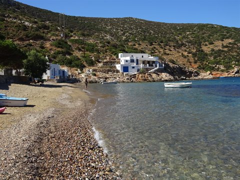 Pebble beach with boats and whitewashed houses in Sifnos