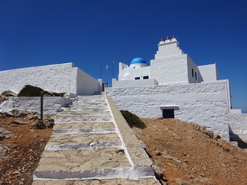 Stone stairs leading to whitewashed church with blue dome in Sifnos