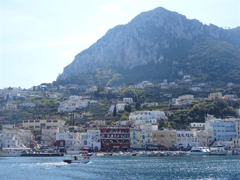 Boats in Capri harbor below Monte Solaro, colorful waterfront houses