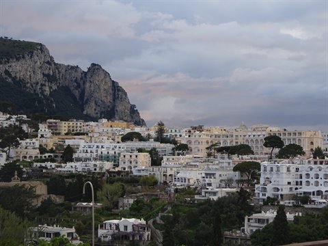 Capri's white houses beneath rocky cliffs under cloudy skies