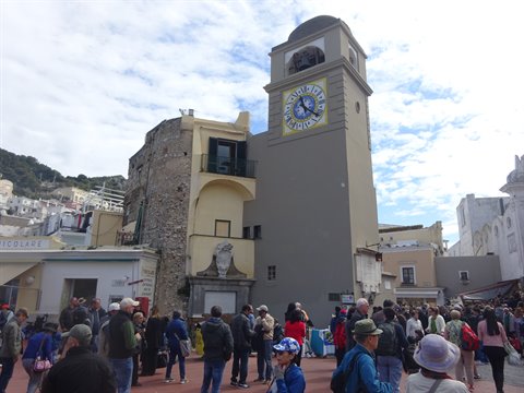 Crowds of tourists fill Capri's Piazzetta beneath the clock tower