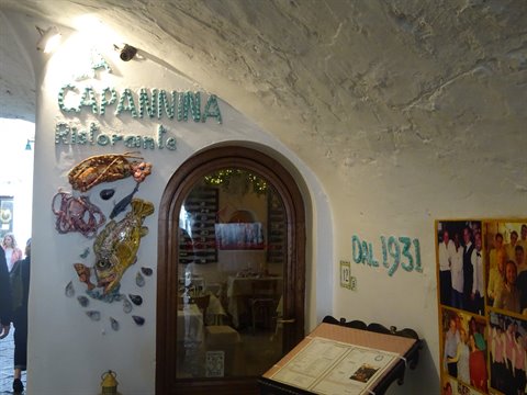 Entrance of La Capannina restaurant with green sign and ceramic decorations, since 1931
