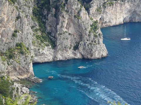 Boats on turquoise water beneath Capri's limestone cliffs