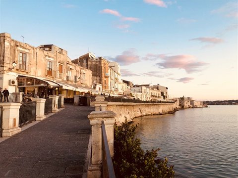 Seafront promenade in Ortigia, Syracuse, old buildings by the water at dusk