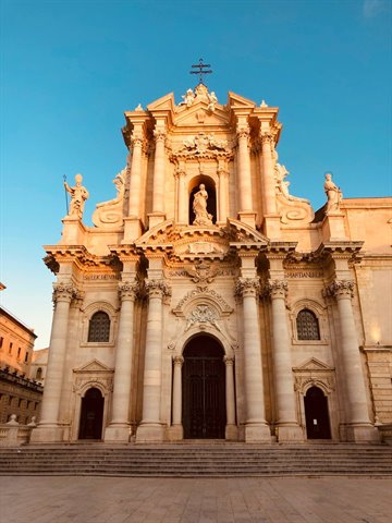 Baroque facade of Syracuse Cathedral in golden stone under blue sky