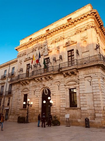 Baroque stone palace with flags on Piazza Duomo in Syracuse
