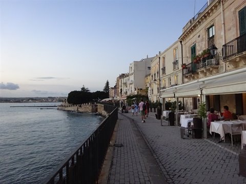 Ortigia seafront in Syracuse: restaurants with set tables beside the calm sea