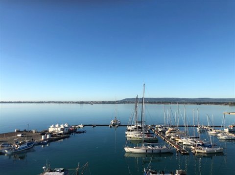 Sailboats moored at the harbor pier, calm sea and blue sky