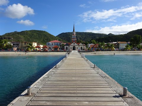 Wooden pier leading to Les Anses-d'Arlet church, turquoise water