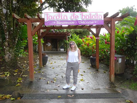 Tourist under the wooden arch of Jardin de Balata, tropical plants and wet path