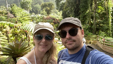 Couple selfie in hats among giant ferns and tropical flowers, Jardin de Balata