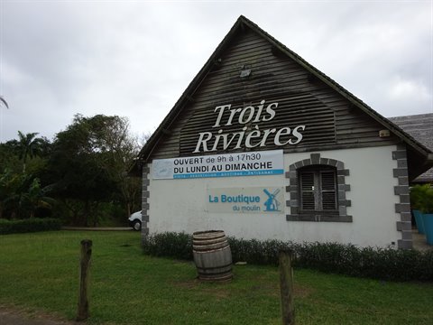 Stone and wood facade of Trois Rivières distillery, with barrel and lawn