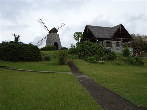 Stone windmill and wooden colonial house among greenery, Martinique