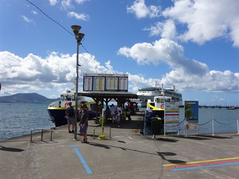 Tourists on the Fort-de-France pier with ferries and a cruise ship