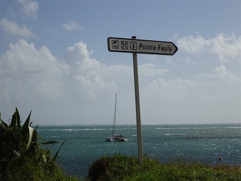 Signpost to Pointe Faula, catamaran anchored in the turquoise sea