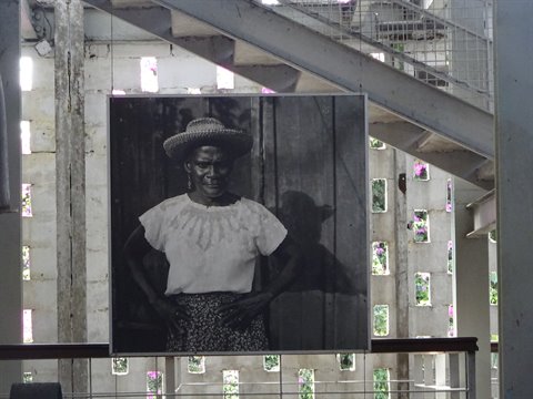 Black and white portrait of a woman in a hat inside an old factory