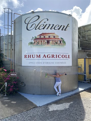 Woman beside the giant steel tank at Clément rhum distillery, Le François