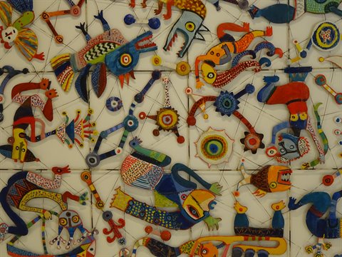 Colorful fabric and ceramic creatures arranged on a white grid installation