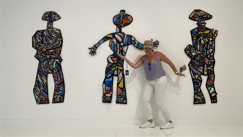 Tourist miming colorful mosaic sculptures on a white gallery wall