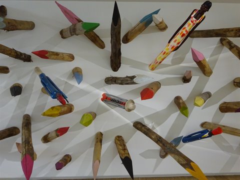 Painted wooden pencils mounted on a white wall, art installation
