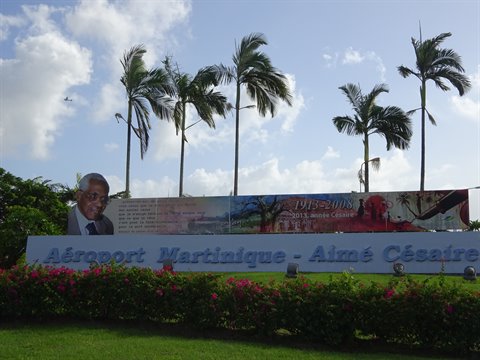 Aimé Césaire airport sign among palm trees and flowers, Fort-de-France