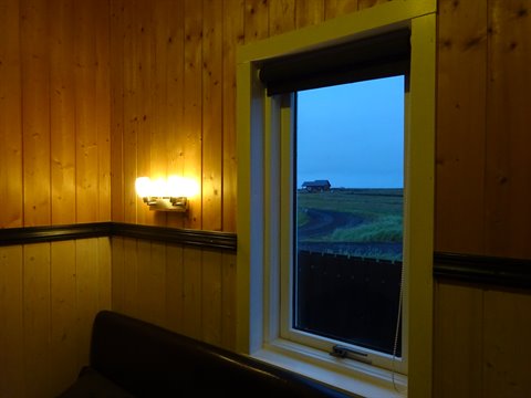Dalla finestra in legno della pensione si vede un casolare isolano nella luce azzurra