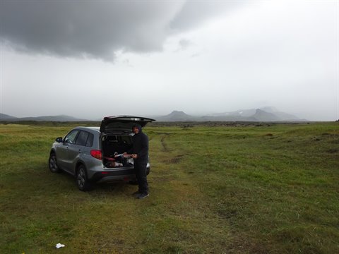 Auto con bagagliaio aperto su prateria verde sotto nuvole minacciose, Reykjanes