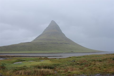 Il monte Kirkjufell affiora dalla nebbia sopra la palude verdeggiante