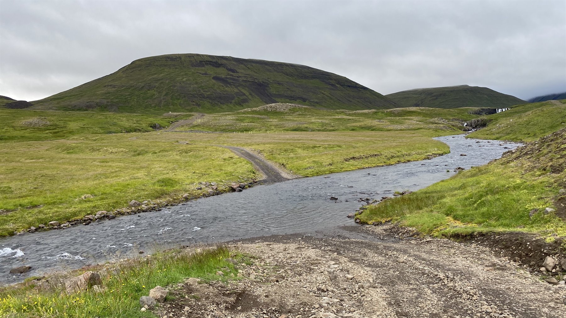 Fiume che scorre tra colline verdi e cieli grigi a Reykjanes