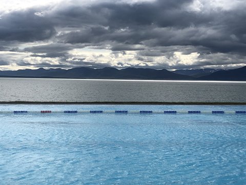 Piscina termale a sfioro davanti al fiordo sotto nuvole grigie, Hofsós