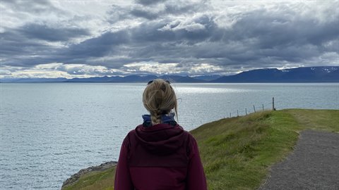 Donna bionda osserva il fiordo grigio tra le nuvole a Siglufjordur