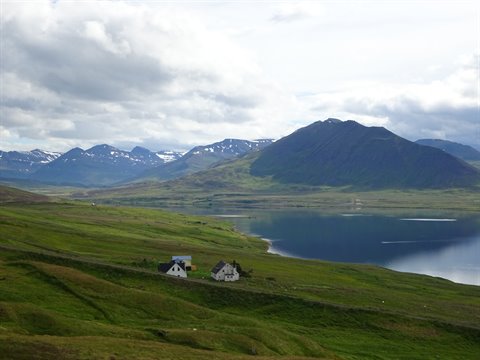 Fattoria isolata sul fiordo verde vicino a Akureyri, nuvole basse sui monti