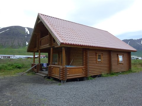 Casetta di tronchi con tetto rosso tra le montagne a Siglufjordur