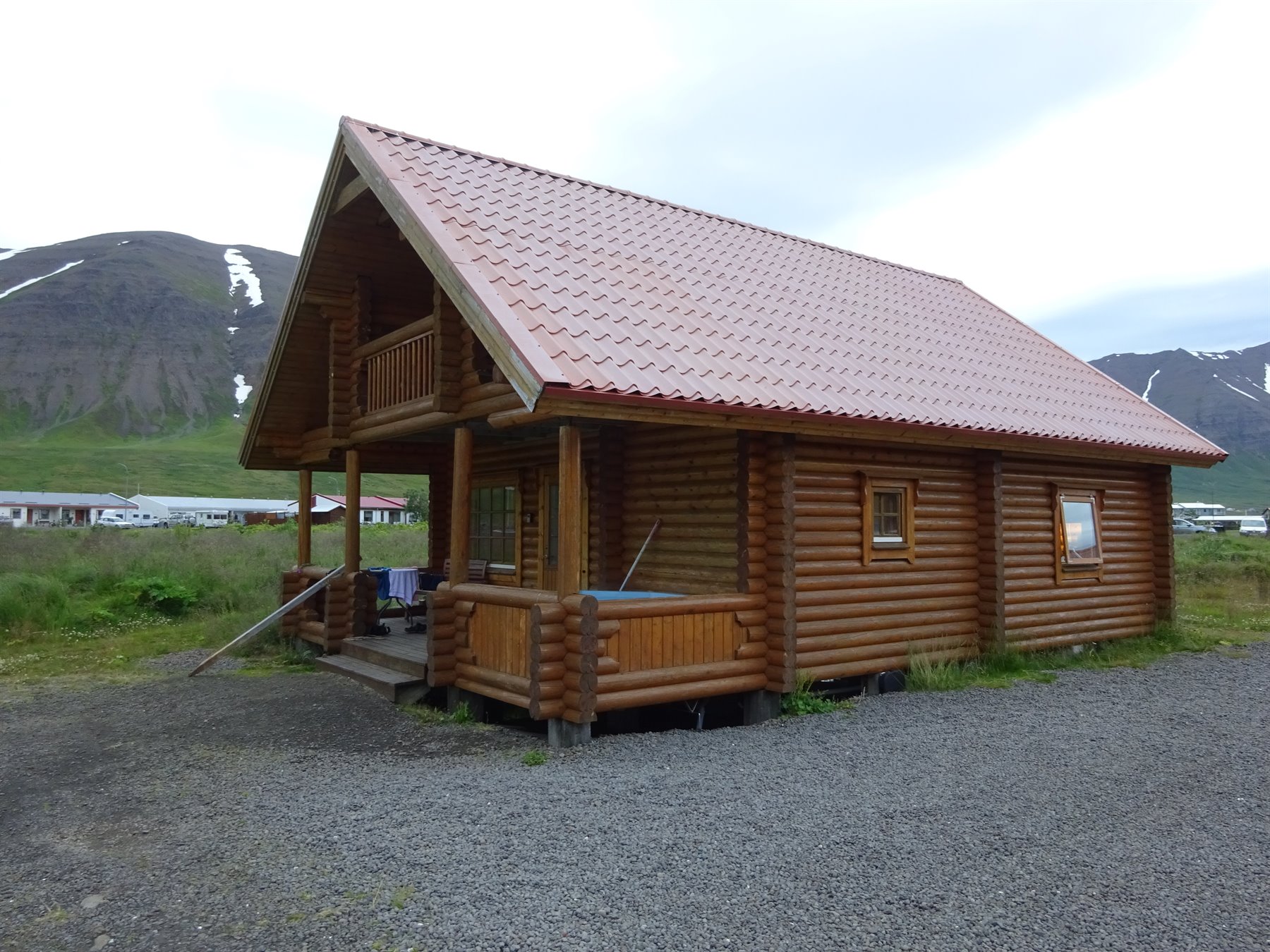 Casetta di tronchi con tetto rosso tra le montagne a Siglufjordur