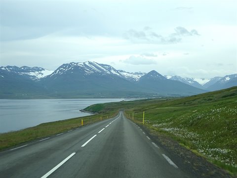 Strada asfaltata lungo il fjord verso le montagne innevate di Akureyri