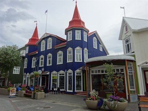 Casa in legno blu con torrette rosse, vassoi di fiori, Akureyri